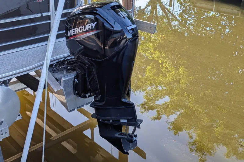 Slide: The Image of 2021 Trifecta 20CLE 2.75 pontoon boat with Mercury outboard motor on calm water. - 10