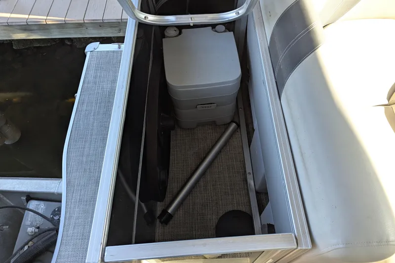 Slide: The Image of Storage compartment in a 2021 Trifecta 20CLE 2.75 pontoon boat, featuring a portable toilet. - 16