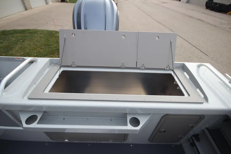 Slide: The Image of 2025 Weldcraft 240 Maverick DV boat storage compartment, open and empty, on a paved surface. - 12