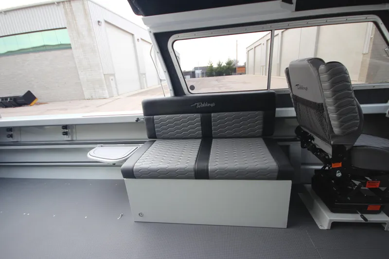 Slide: The Image of 2025 Weldcraft 240 Maverick DV boat interior with gray seating and window view. - 25