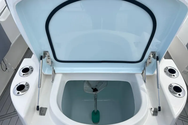 Slide: The Image of Open storage compartment on 2015 Cape Horn 32 XS boat, featuring rod holders and hydraulic hinges. - 17