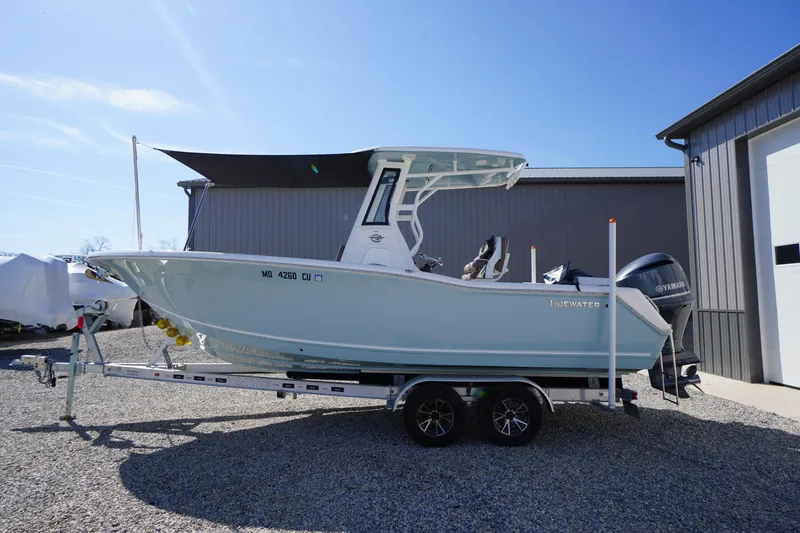 Slide: The Image of 2024 Tidewater 232 LXF boat on trailer, parked outdoors under clear blue sky. - 2