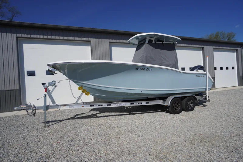 Slide: The Image of 2024 Tidewater 232 LXF boat on trailer, parked outside a garage. - 4