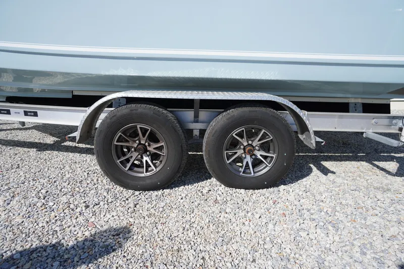 Slide: The Image of Trailer wheels of a 2024 Tidewater 232 LXF boat on gravel surface. - 43