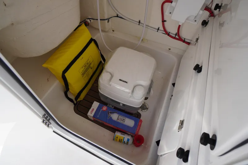 Slide: The Image of 2024 Tidewater 232 LXF boat interior with portable toilet and safety equipment. - 49