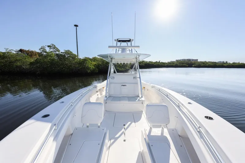 Slide: The Image of 2016 Invincible 39 Open Fisherman boat on calm water, sunny day, lush greenery background. - 15