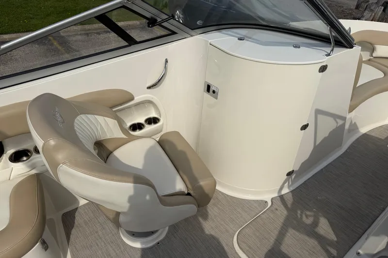 Slide: The Image of 2016 Stingray 215 LR boat interior with beige and white seating, cup holders, and dashboard. - 15