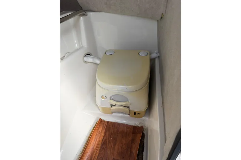Slide: The Image of 2016 Stingray 215 LR boat interior with portable toilet and wood flooring. - 16
