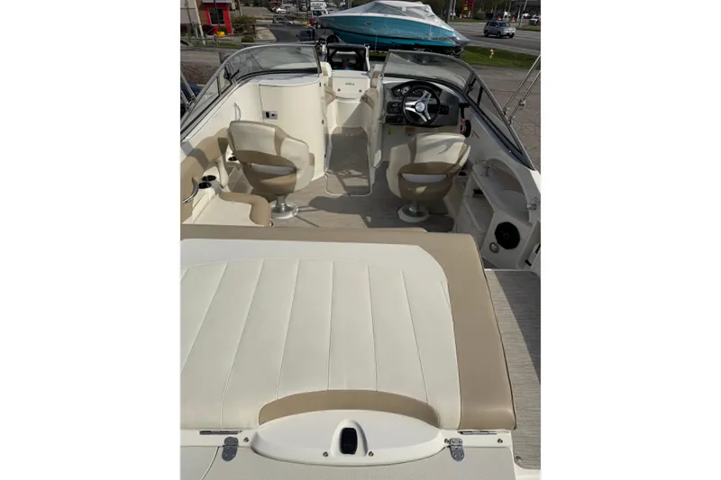 Slide: The Image of 2016 Stingray 215 LR boat interior with beige seating and steering console. - 2