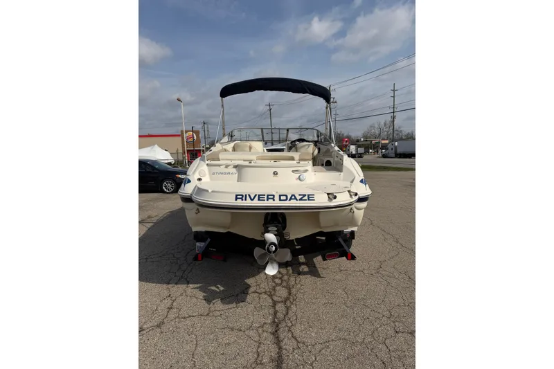 Slide: The Image of 2016 Stingray 215 LR boat named "River Daze" parked on pavement under cloudy sky. - 3