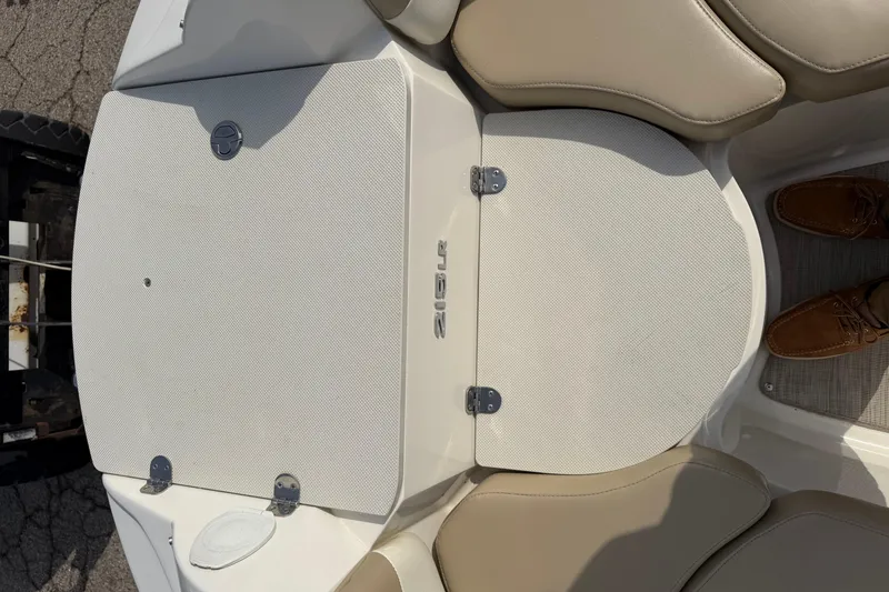 Slide: The Image of 2016 Stingray 215 LR boat interior with beige seating and storage compartment. - 4