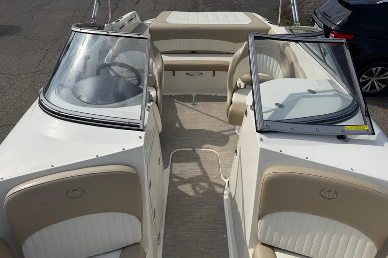 Slide: The Image of 2016 Stingray 215 LR boat interior with beige and white seating, dual windshields, and steering wheel. - 7