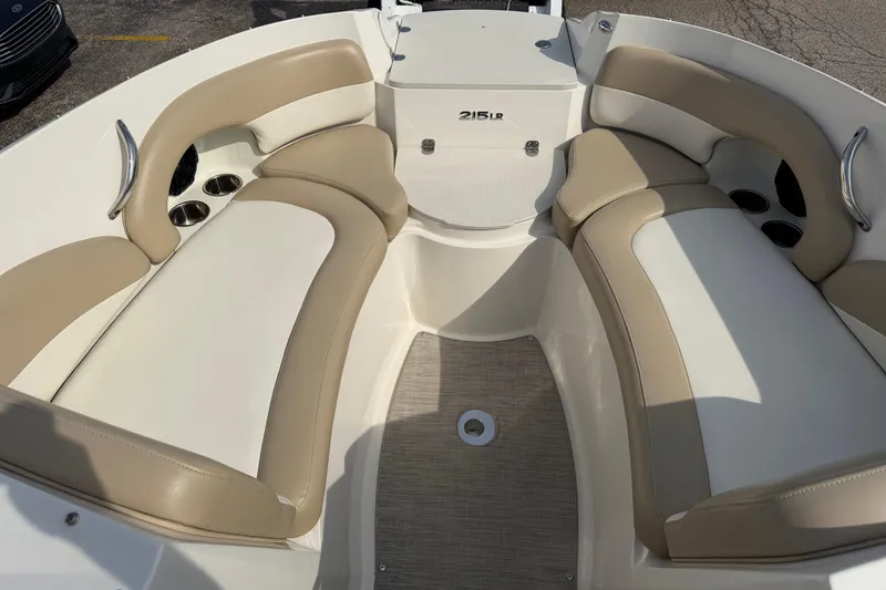 Slide: The Image of 2016 Stingray 215 LR boat interior with beige and white seating, cup holders, and stainless steel handles. - 9