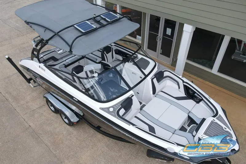 Slide: The Image of 2017 Yamaha Boats 242X E-Series with canopy and trailer, parked outside a building. - 3