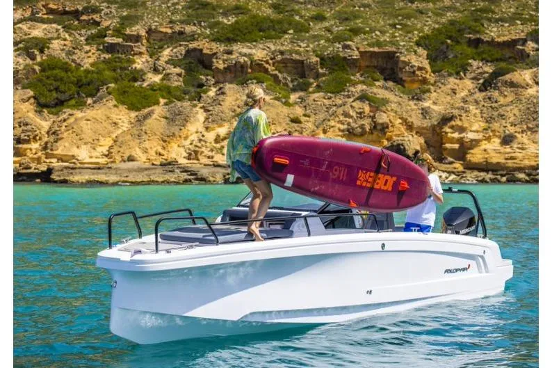 Slide: The Image of 2027 Axopar 25 Cross Bow on turquoise water, people loading a surfboard. - 4