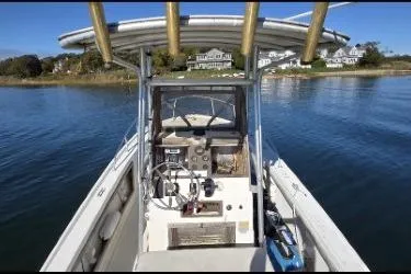 Slide: The Image of 1987 Mako 212 Center Console boat on calm water, featuring a steering console and T-top. - 5