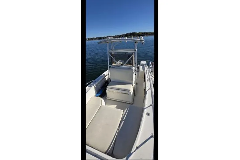 Slide: The Image of 1987 Mako 212 Center Console boat on calm water, featuring spacious seating and canopy. - 9