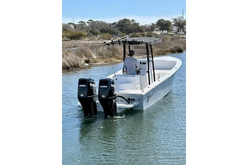 Slide: The Image of 2025 C-Hawk 26 Center Console boat with dual Suzuki engines navigating a waterway. - 3