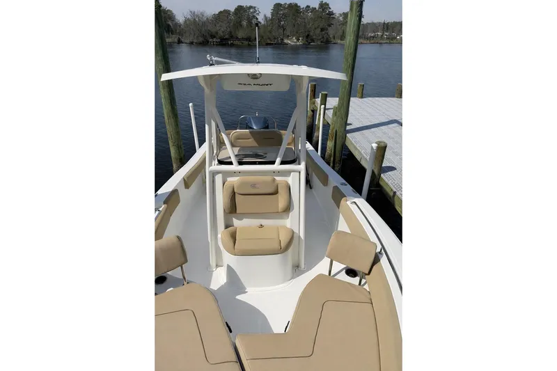 Slide: The Image of 2018 Sea Hunt Ultra 234 boat with tan seating, docked by a calm lake. - 3