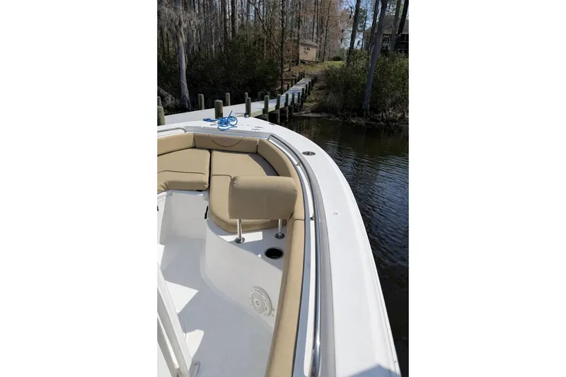 Slide: The Image of 2018 Sea Hunt Ultra 234 boat with tan seating, docked near a wooded shoreline. - 7