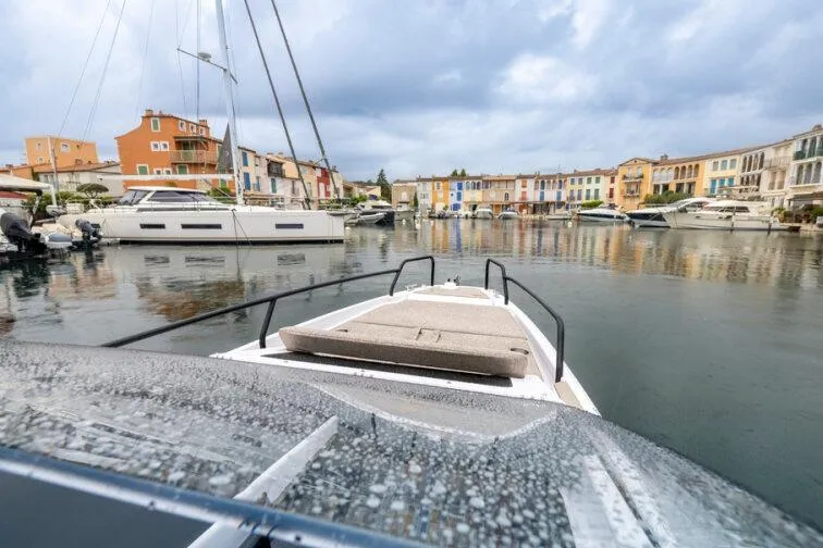Slide: The Image of 2027 Axopar 25 Cross Top boat in a colorful marina setting. - 2