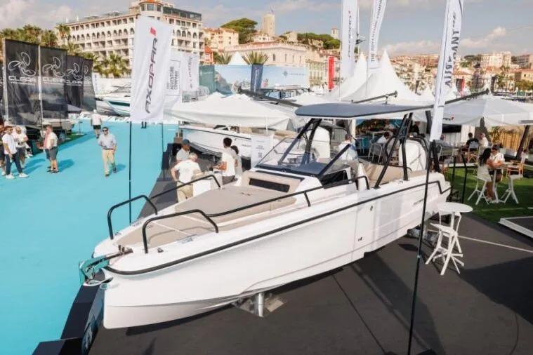 Slide: The Image of 2027 Axopar 25 Cross Top boat displayed at a marina event with people and banners. - 5