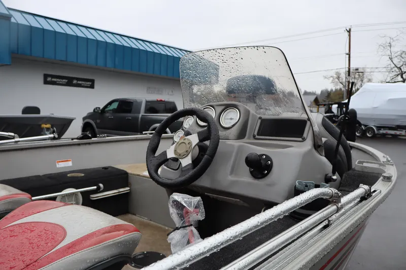 Slide: The Image of 2009 Lowe Fishing Machine 165 boat interior with steering wheel and dashboard, wet from rain. - 13