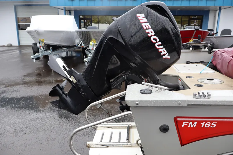 Slide: The Image of 2009 Lowe Fishing Machine 165 with Mercury outboard motor, parked on wet pavement. - 14