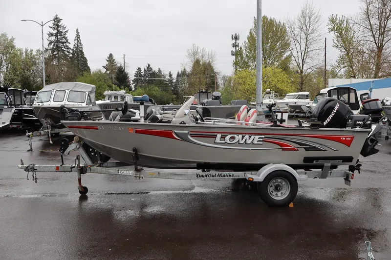 Slide: The Image of 2009 Lowe Fishing Machine 165 boat on trailer in a parking lot. - 3