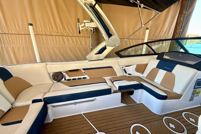 Slide: The Image of 2022 MasterCraft X24 boat interior with tan and navy seating, wood flooring. - 13