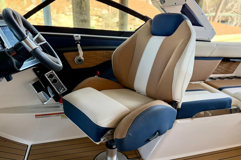Slide: The Image of 2022 MasterCraft X24 boat interior with tan and blue captain's seat and steering wheel. - 17