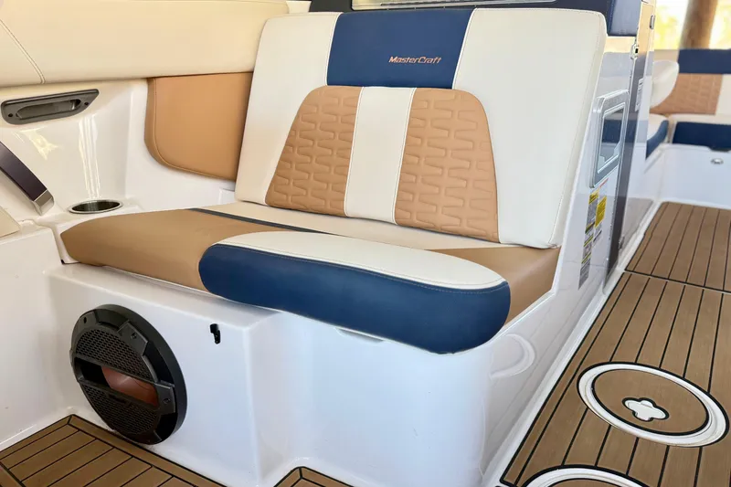 Slide: The Image of 2022 MasterCraft X24 boat interior with tan and blue seating, featuring premium upholstery. - 22