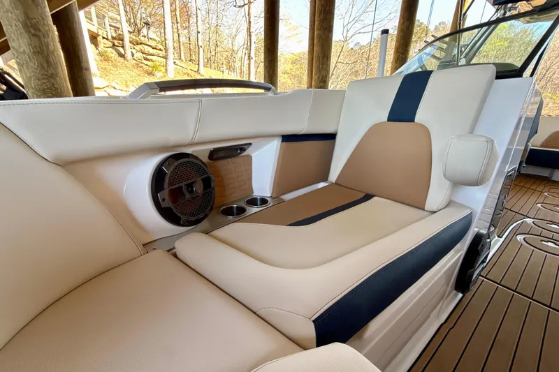 Slide: The Image of 2022 MasterCraft X24 boat interior with beige and navy seating, speaker, and cup holders. - 24