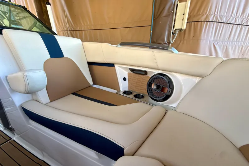 Slide: The Image of 2022 MasterCraft X24 boat interior with beige and blue seating, cup holders, and speaker. - 25