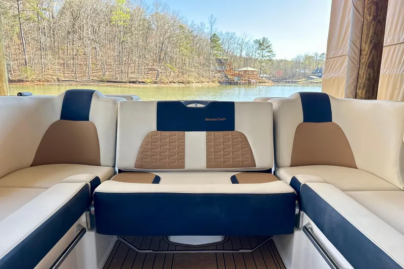 Slide: The Image of 2022 MasterCraft X24 boat interior with luxurious seating by a serene lake. - 29