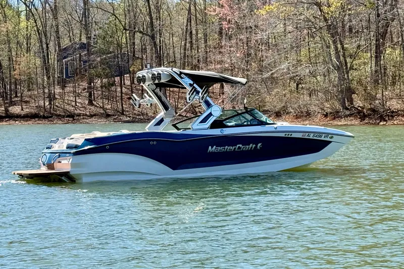 Slide: The Image of 2022 MasterCraft X24 boat on a serene lake with wooded shoreline. - 5