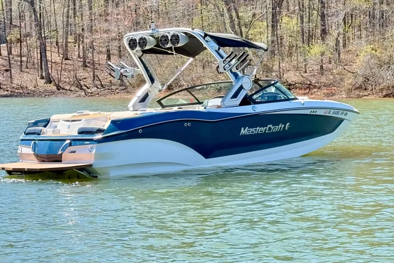 Slide: The Image of 2022 MasterCraft X24 boat on a serene lake with wooded shoreline. - 6