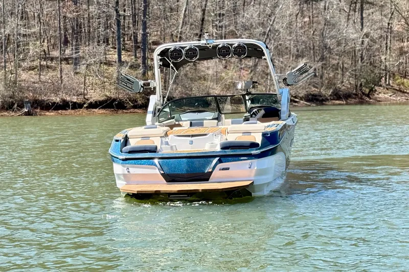 Slide: The Image of 2022 MasterCraft X24 boat on a calm lake with wooded shoreline background. - 7