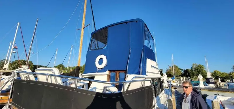 Slide: The Image of 1983 Carver 3207 Aft Cabin with blue canopy in harbor. - 2
