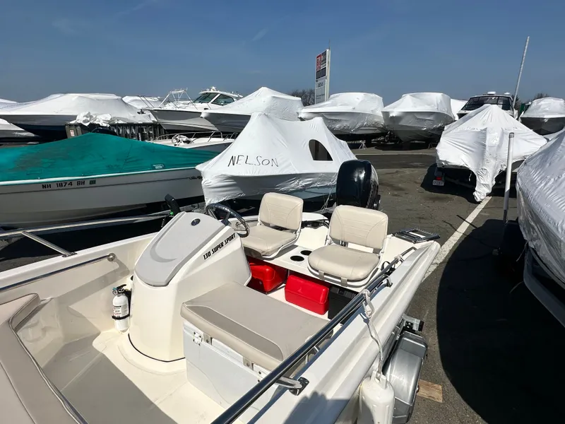 Slide: The Image of 2019 Boston Whaler 130 Super Sport boat in parking lot with covers. - 7