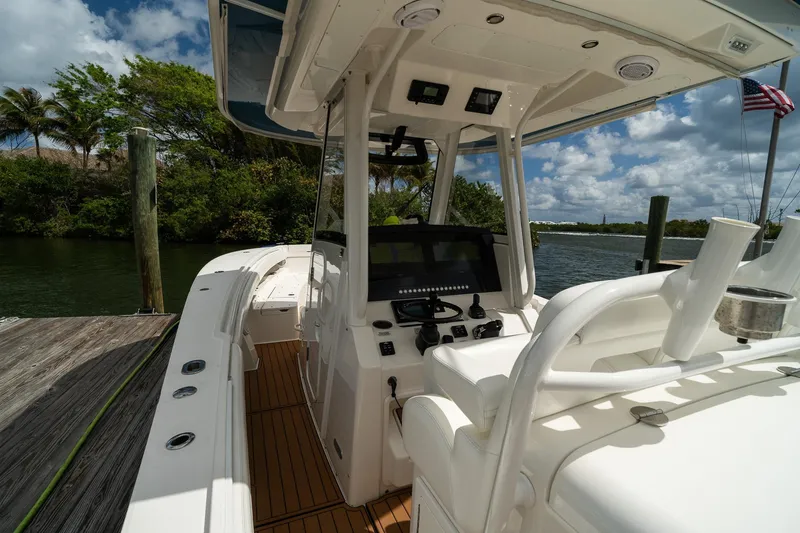 Slide: The Image of 2020 Regulator 31 boat interior at dock, featuring helm and seating under clear skies. - 11
