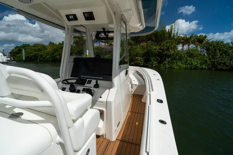 Slide: The Image of 2020 Regulator 31 boat interior with helm, white seating, and wooden deck. - 13