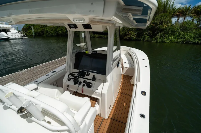 Slide: The Image of 2020 Regulator 31 boat interior with helm, docked by lush greenery. - 14