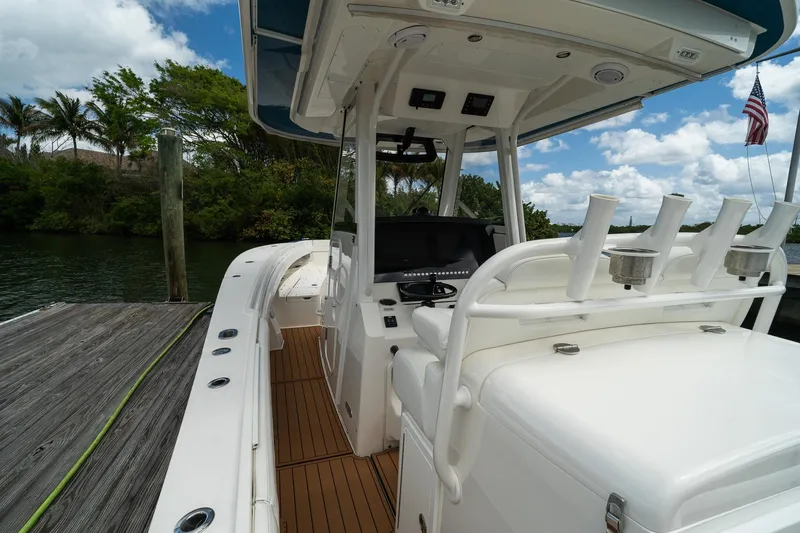 Slide: The Image of 2020 Regulator 31 boat docked, featuring helm station and rod holders, under a blue sky. - 17