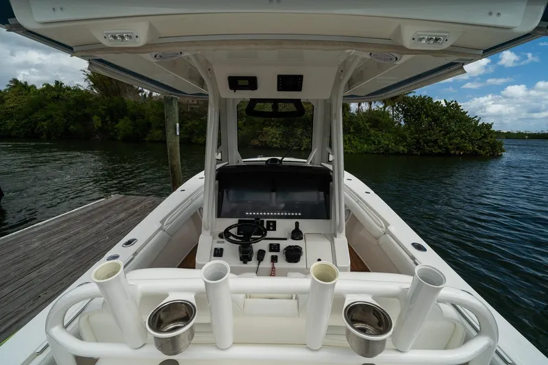 Slide: The Image of 2020 Regulator 31 boat cockpit with control panel, docked by lush greenery and calm waters. - 19