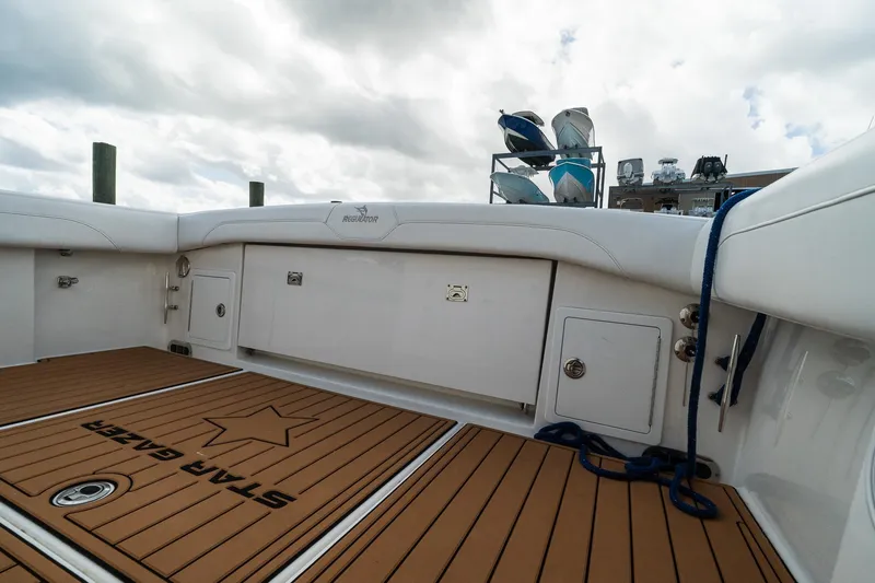 Slide: The Image of 2020 Regulator 31 boat deck with storage compartments and teak flooring under cloudy sky. - 27