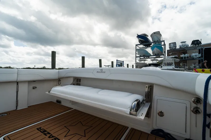 Slide: The Image of 2020 Regulator 31 boat interior with cushioned seating and wooden deck, under cloudy sky. - 32