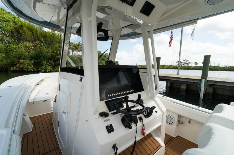 Slide: The Image of 2020 Regulator 31 boat cockpit with modern controls, docked by a scenic waterfront. - 34