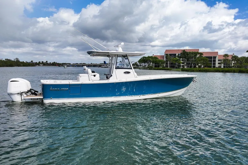 Slide: The Image of 2020 Regulator 31 boat on water, blue hull, cloudy sky, waterfront buildings in background. - 4