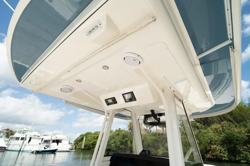 Slide: The Image of 2020 Regulator 31 boat canopy with speakers and lights, docked near lush greenery. - 45